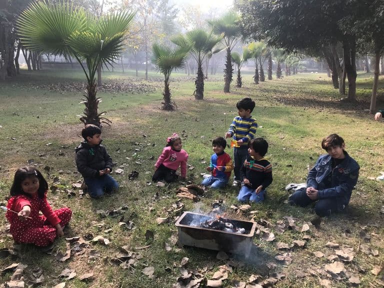 Children engaged in outdoor sand play under tree shade